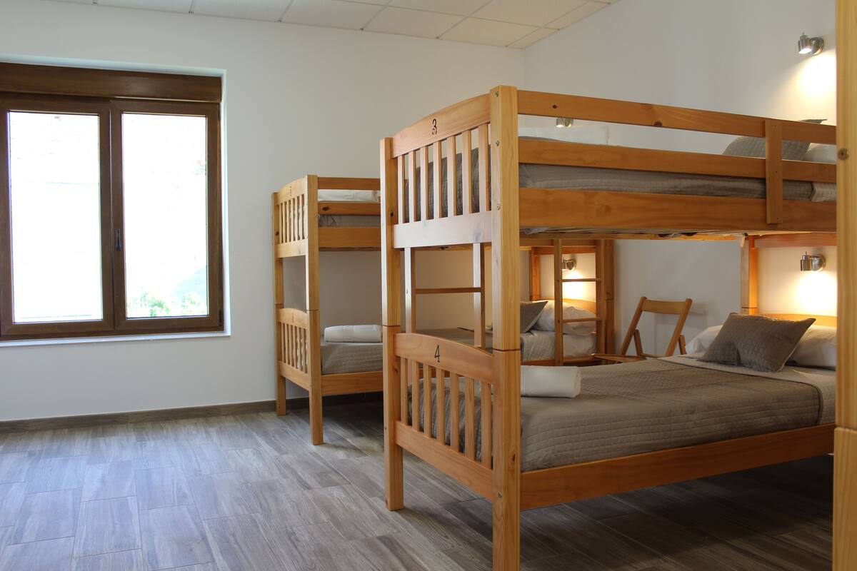 Ein Zimmer mit zwei Etagenbetten, einem Fenster und einem Nachttisch mit Lampe.