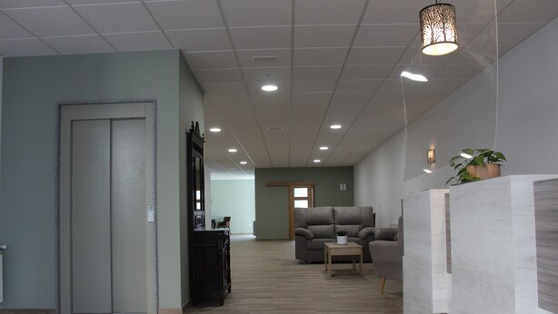 Un hall d’entrée spacieux avec un plancher en bois, un comptoir d’accueil, un canapé et une porte donnant sur une autre pièce.