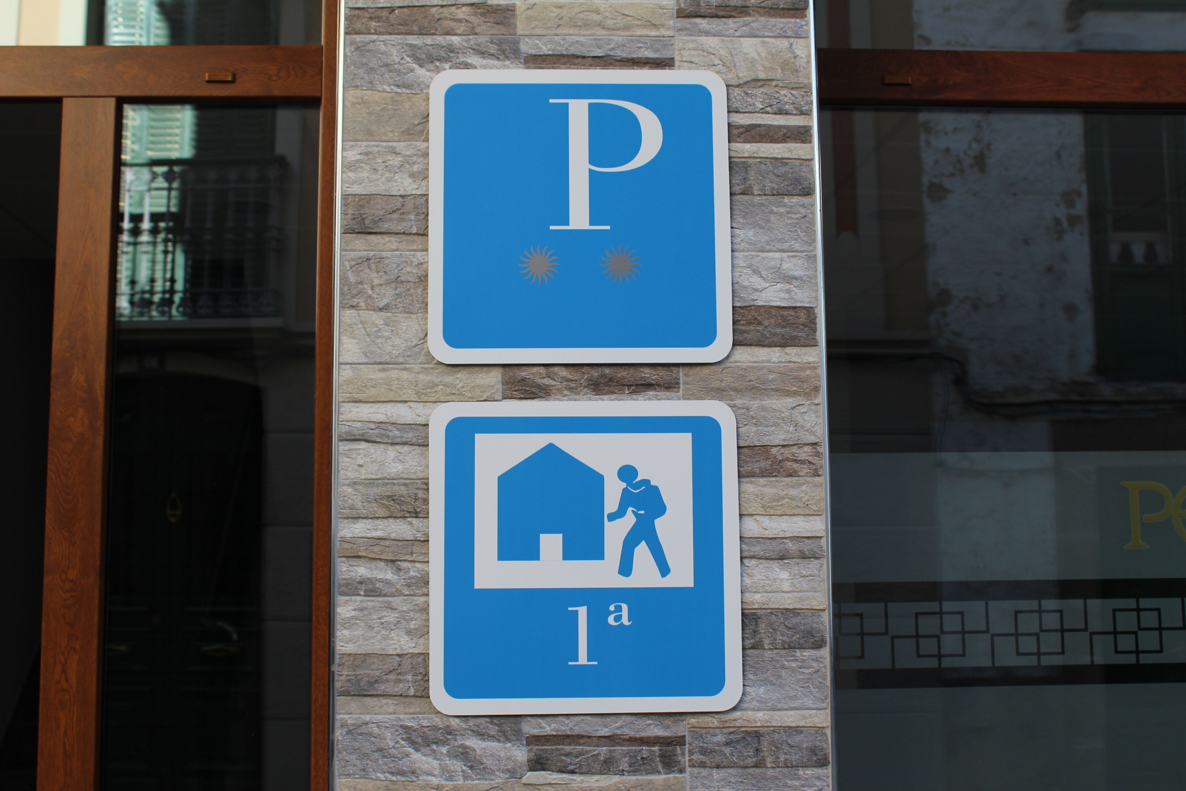 A parking sign with a 'P' and a symbol of a person with a backpack entering a house, indicating a parking area for visitors.