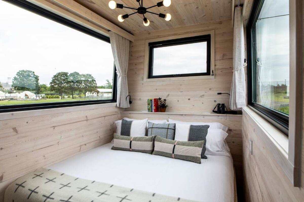 Un dormitorio acogedor con interior de madera, un ventanal grande y vistas al exterior.