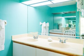 Une salle de bain avec deux lavabos, un miroir et des serviettes accrochées au mur.
