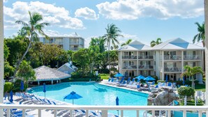 Un complexe hôtelier doté d’une piscine, de chaises longues, de parasols et de palmiers.