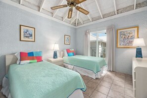 Ein Hotelzimmer mit zwei Betten, einem Deckenventilator und Blick ins Freie.