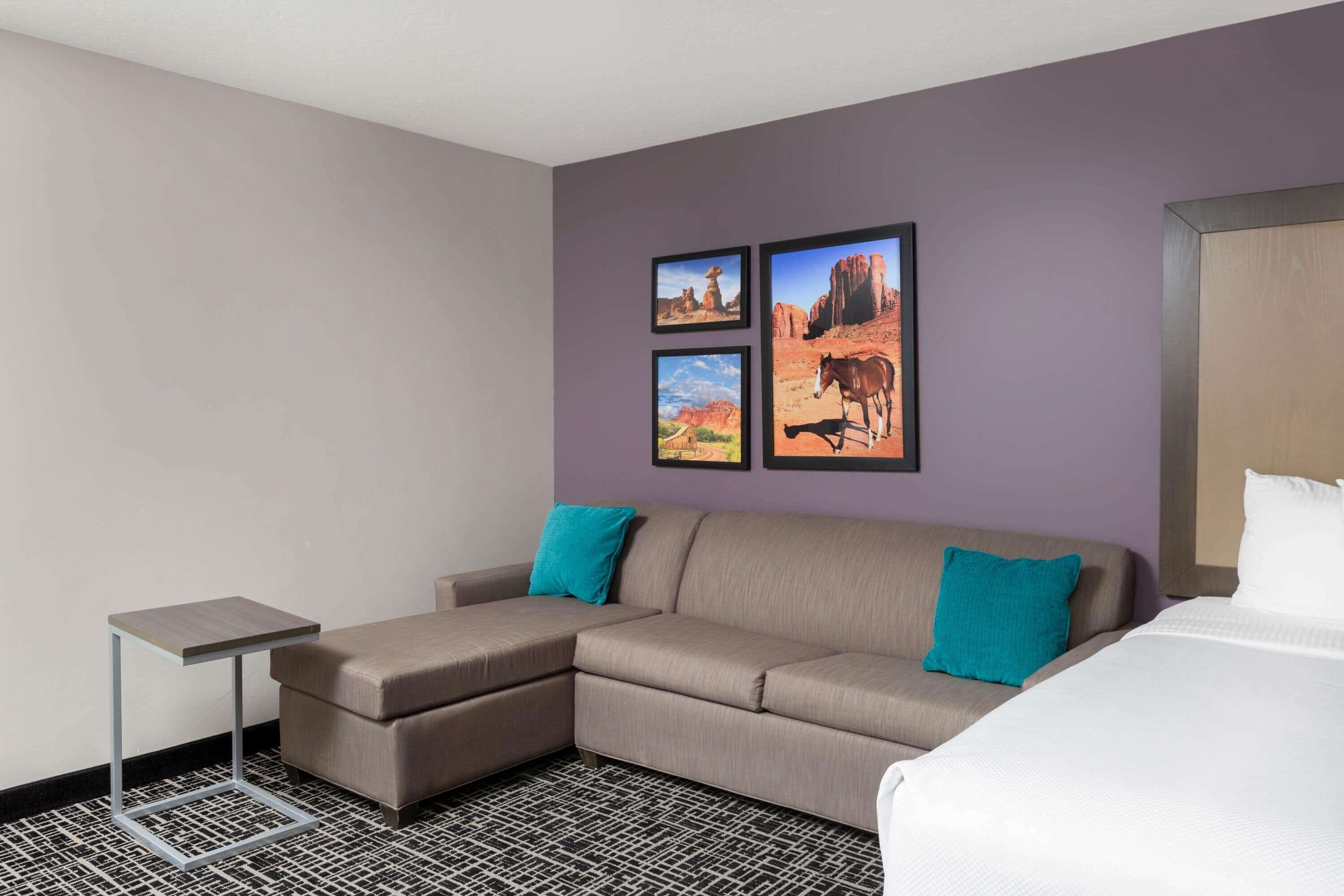 Ein Hotelzimmer mit einer Eckcouch, einem kleinen Beistelltisch und einem Bett.