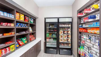 A grocery store with shelves stocked with snacks, beverages, and household items.
