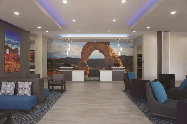 Eine Lobby mit einer Rezeption, einer Sitzecke und einer großflächigen Felsbogen-Mural.
