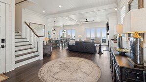 A spacious living area with a staircase, a large round rug, and a dining area with a table and chairs.