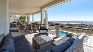 A covered outdoor area with a pool, seating, and a view of the ocean.
