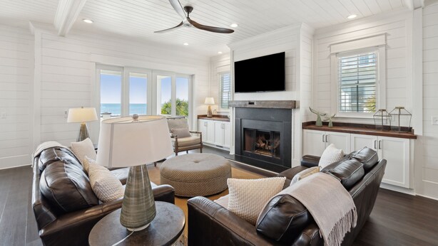 A spacious living room with a fireplace, leather sofas, and a television.