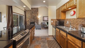 Una cocina moderna con una pared de acento de piedra, armarios de madera y un microondas integrado.