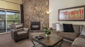 Una sala de estar con chimenea de piedra, un sofá, un sillón y una mesa de centro.