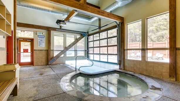 Una piscina interior con techo de madera y grandes ventanales.