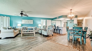 A spacious living room with a sofa, armchairs, and a dining area with a table and chairs.