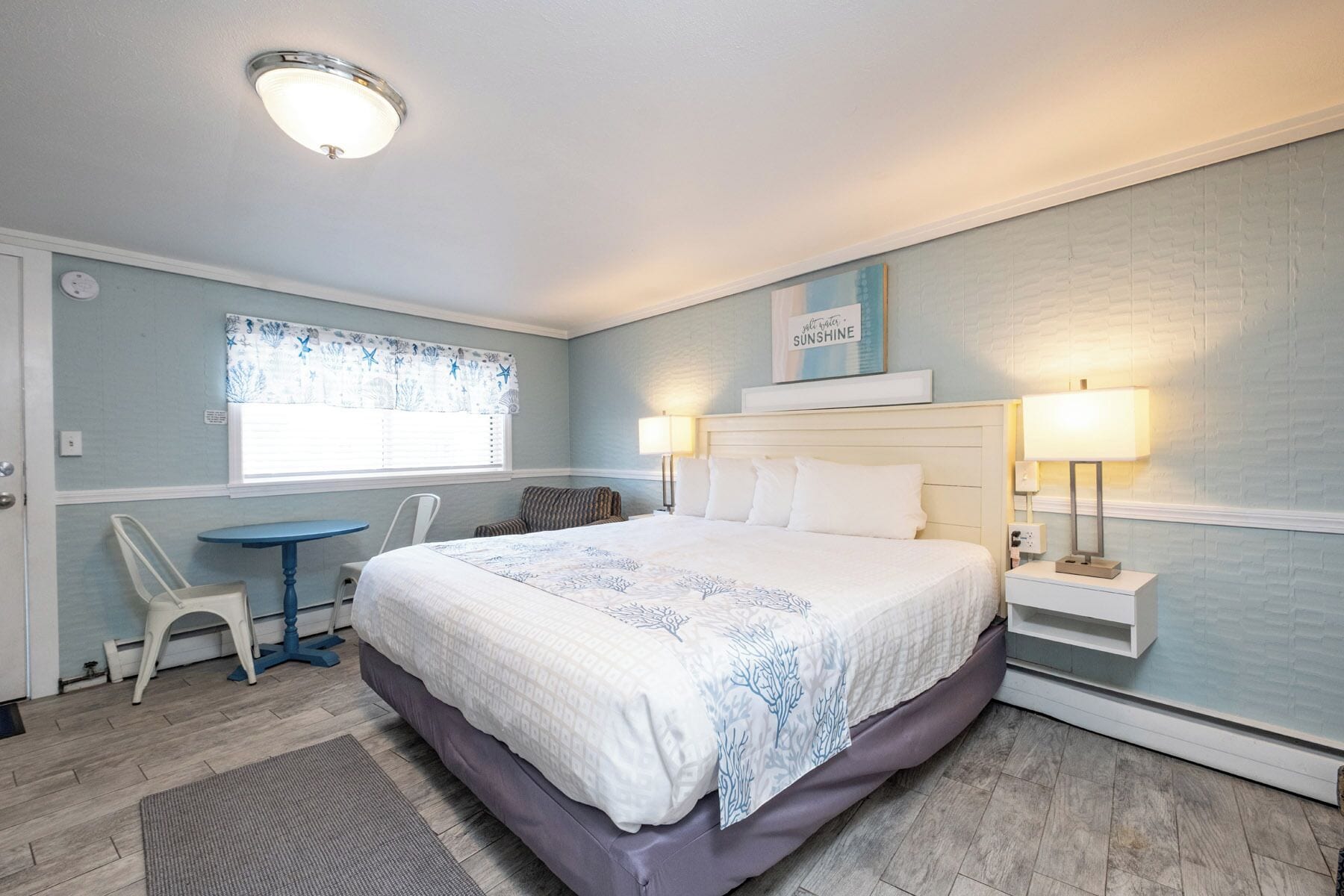 Une chambre à coucher avec un lit, des lampes de chevet, une petite table et une chaise.
