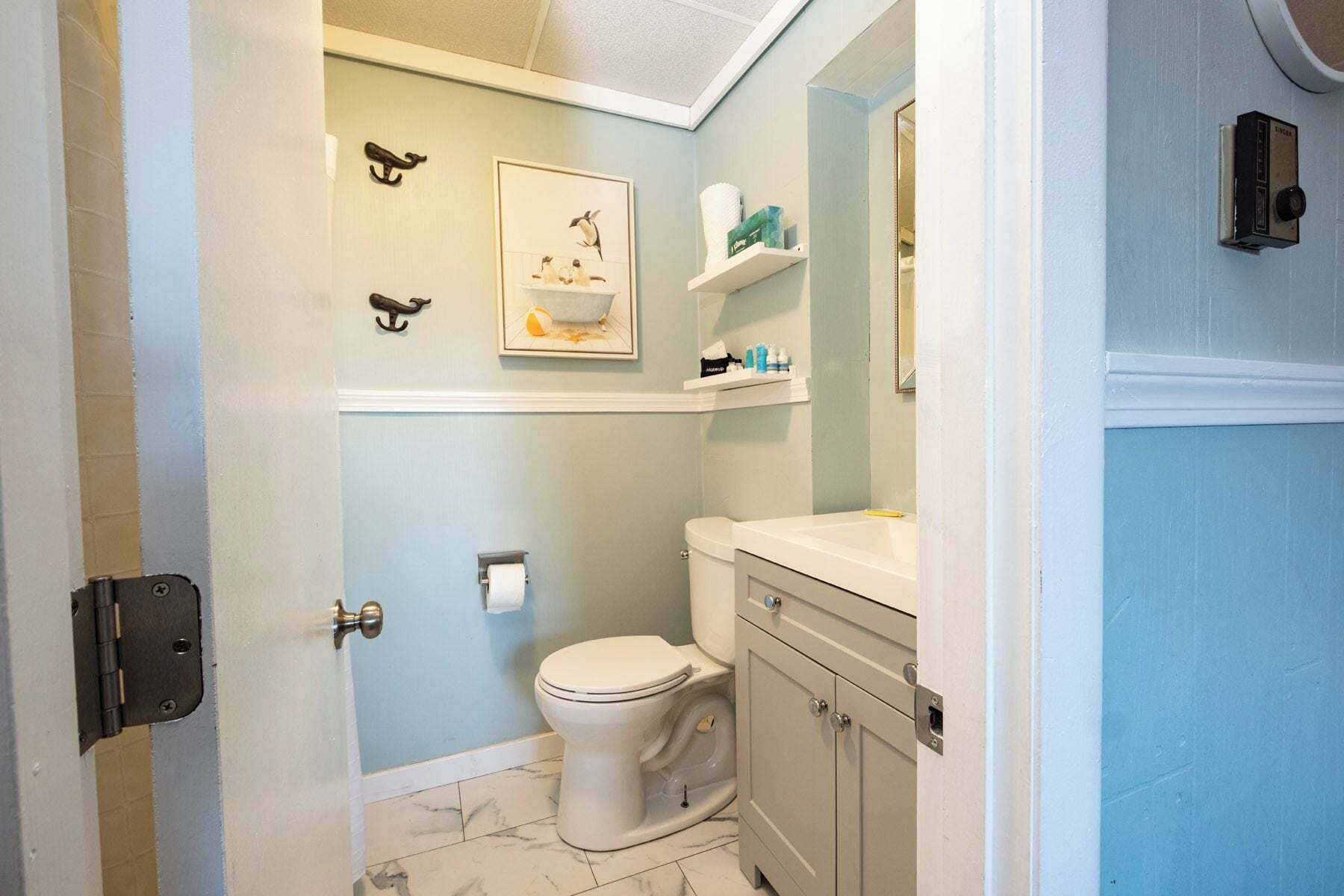 A bathroom with a toilet, a sink, a mirror, and a shelf with toiletries.