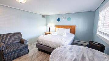 A hotel room with a bed, a sofa, a round table, and a lamp.