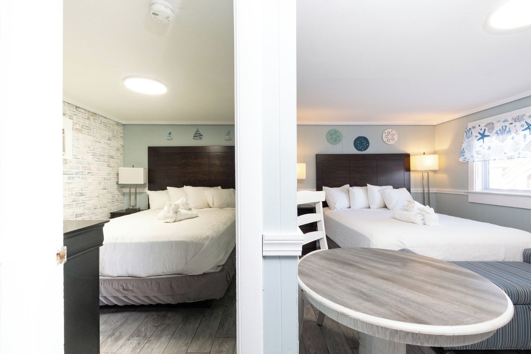Habitación de hotel con dos camas, una mesita y decoración náutica.