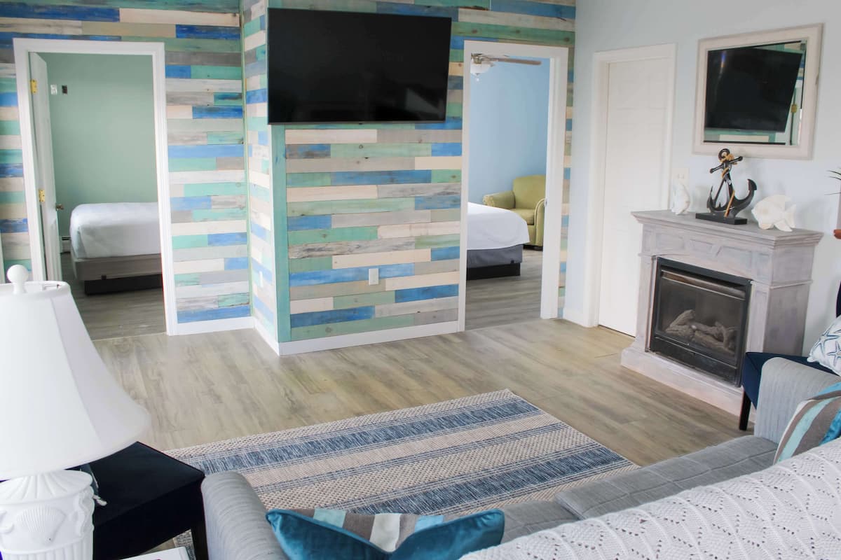 A room with a bed, a sofa, a fireplace, and a television mounted on the wall.