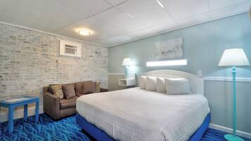 Habitación de hotel con una cama grande, un pequeño sofá, una mesita de noche y una lámpara.