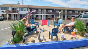 Un motel con área de piscina, sillas de descanso, un parque infantil y una estatua de sirena.