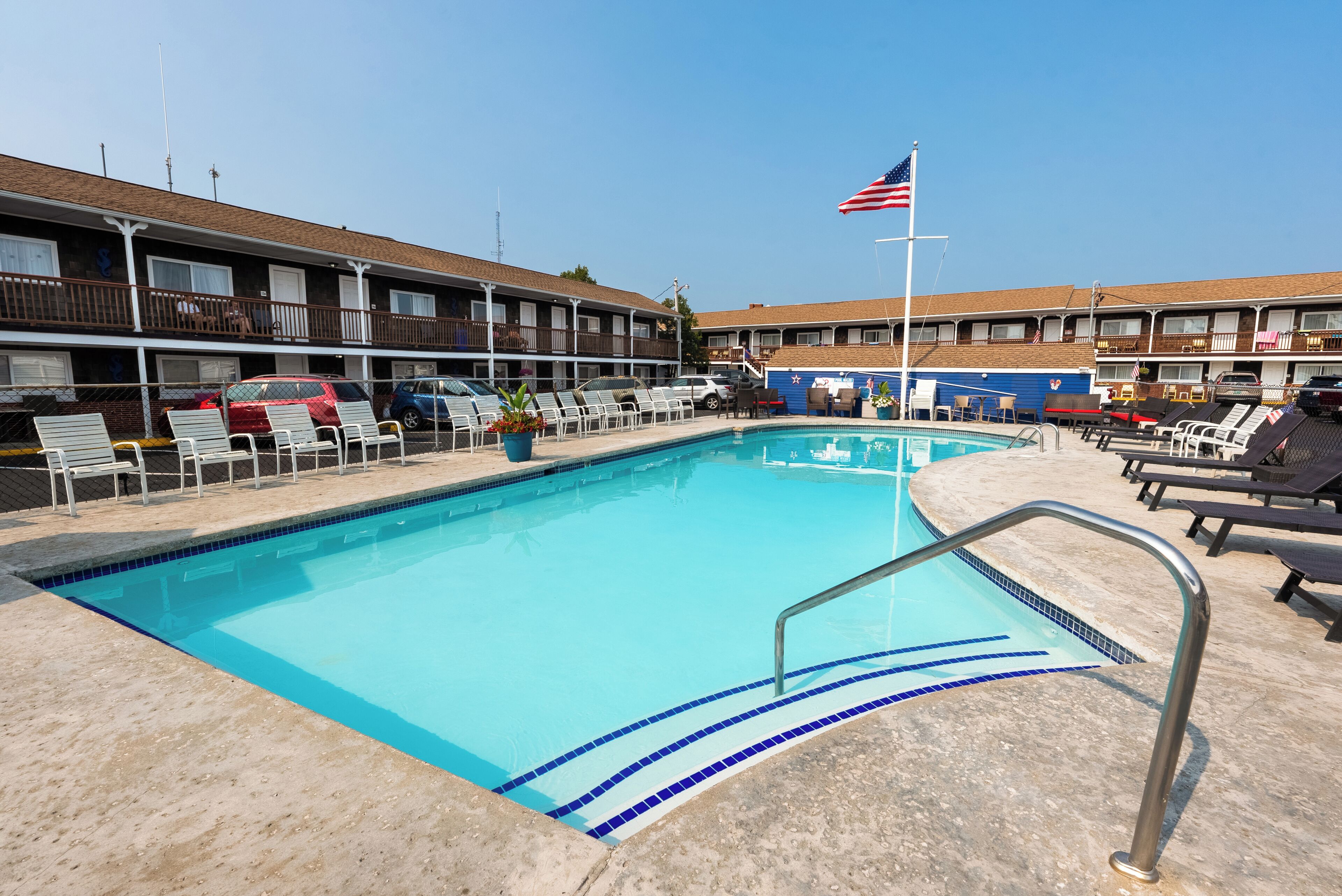 A swimming pool with lounge chairs and a flag.
