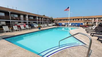 A swimming pool with lounge chairs and a flag.