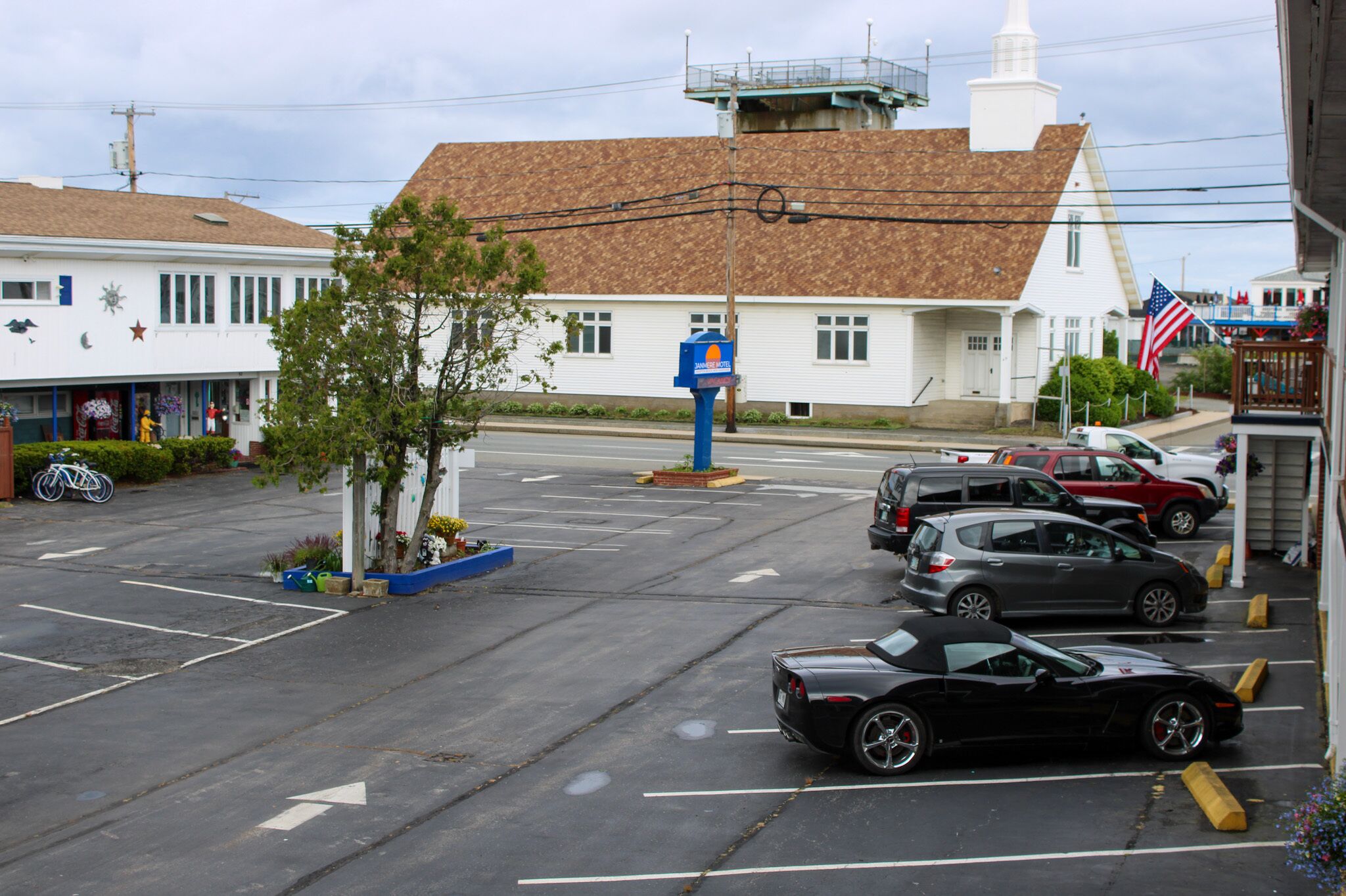 A parking lot with several cars, a building with a brown roof, and a blue mailbox.