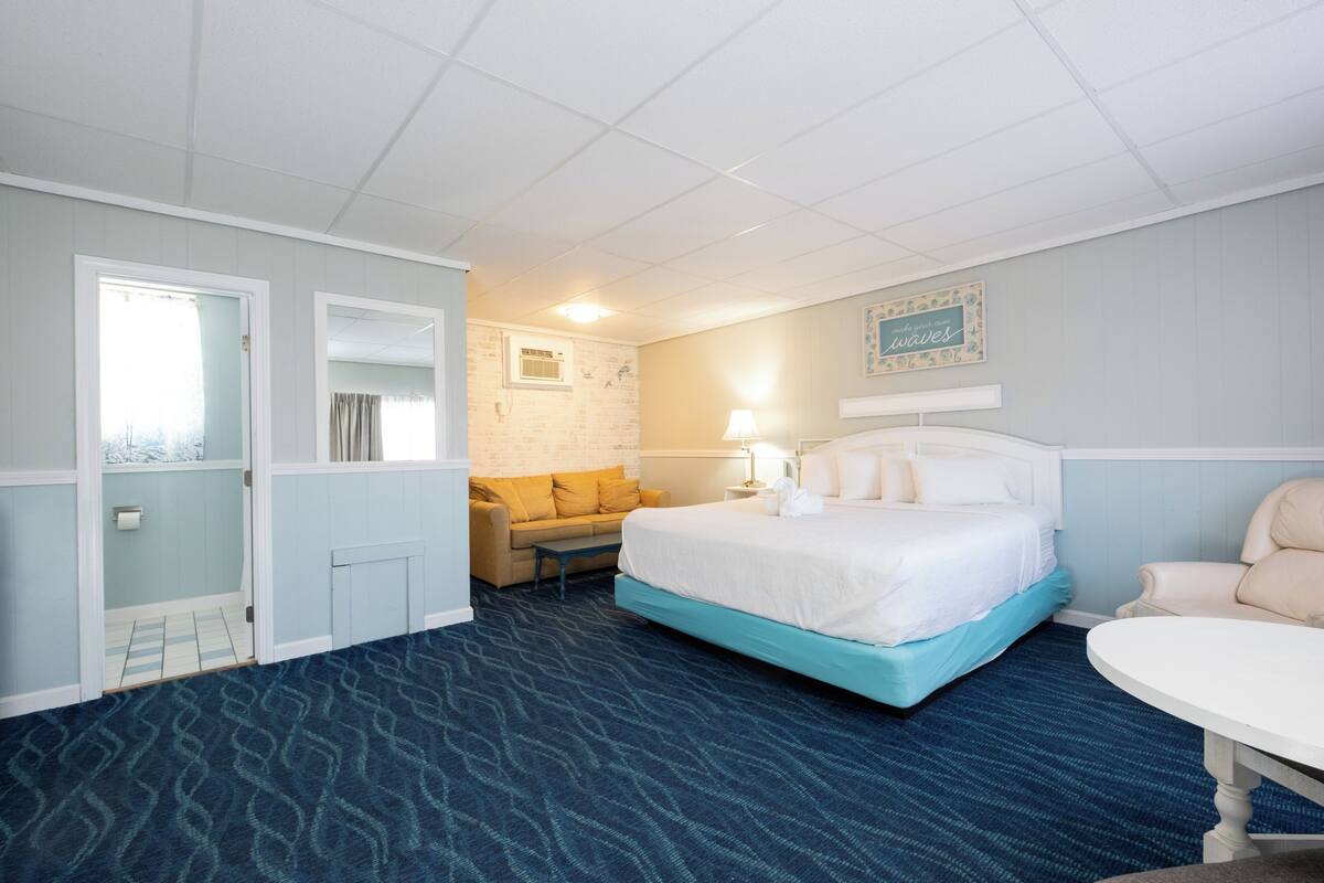 A hotel room with a bed, a sofa, a table, and a wall with a sign.