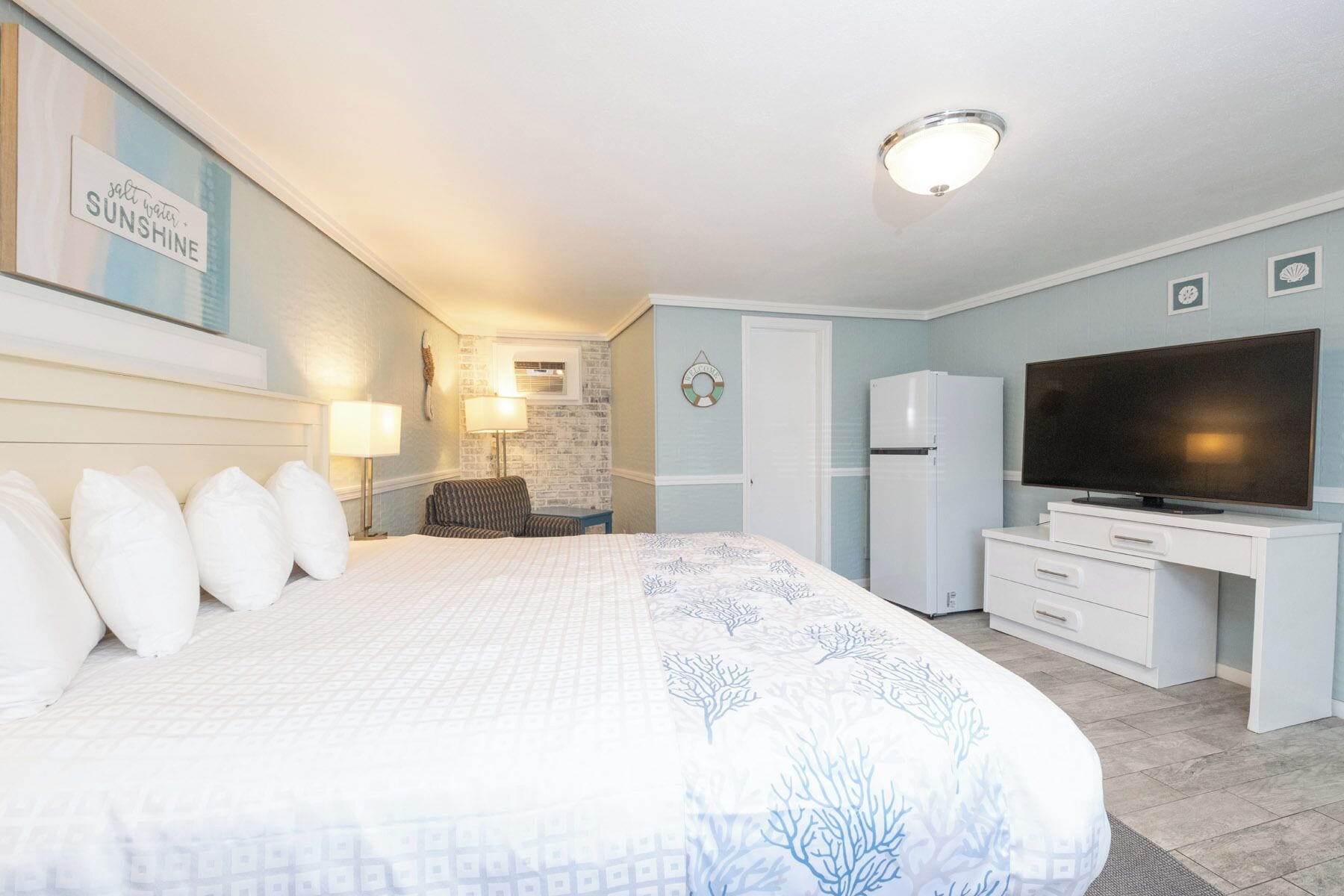 Une chambre d’hôtel équipée d’un lit, d’un bureau, d’une télévision et d’un réfrigérateur.