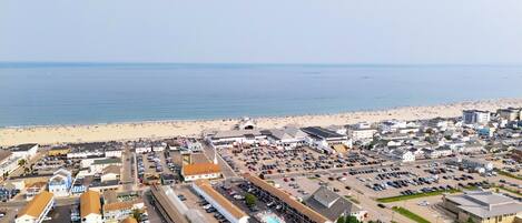 Vista aérea de un pueblo costero con playa, estacionamientos y varios edificios.