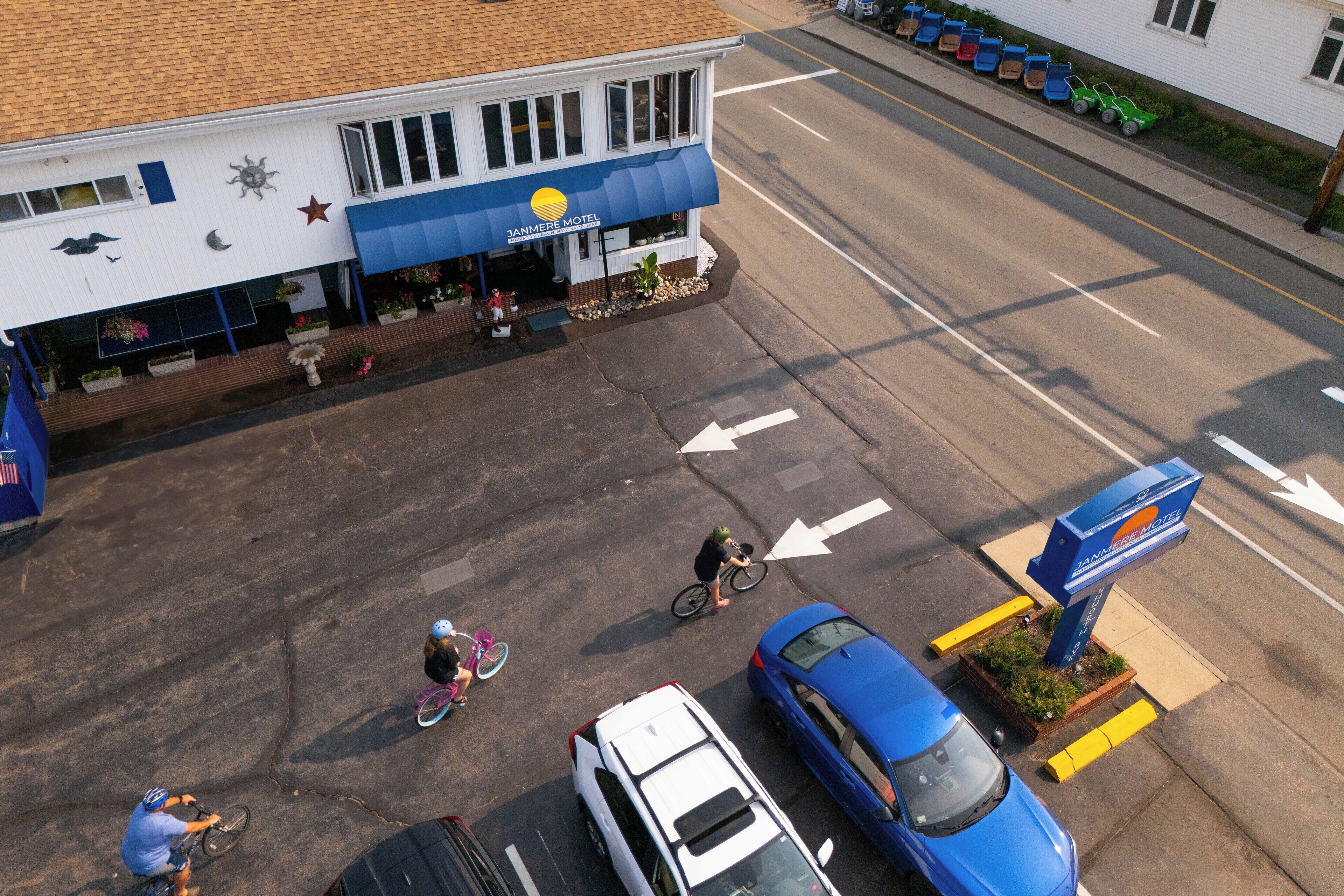 A motel with a blue awning, a parking lot, and a street view.