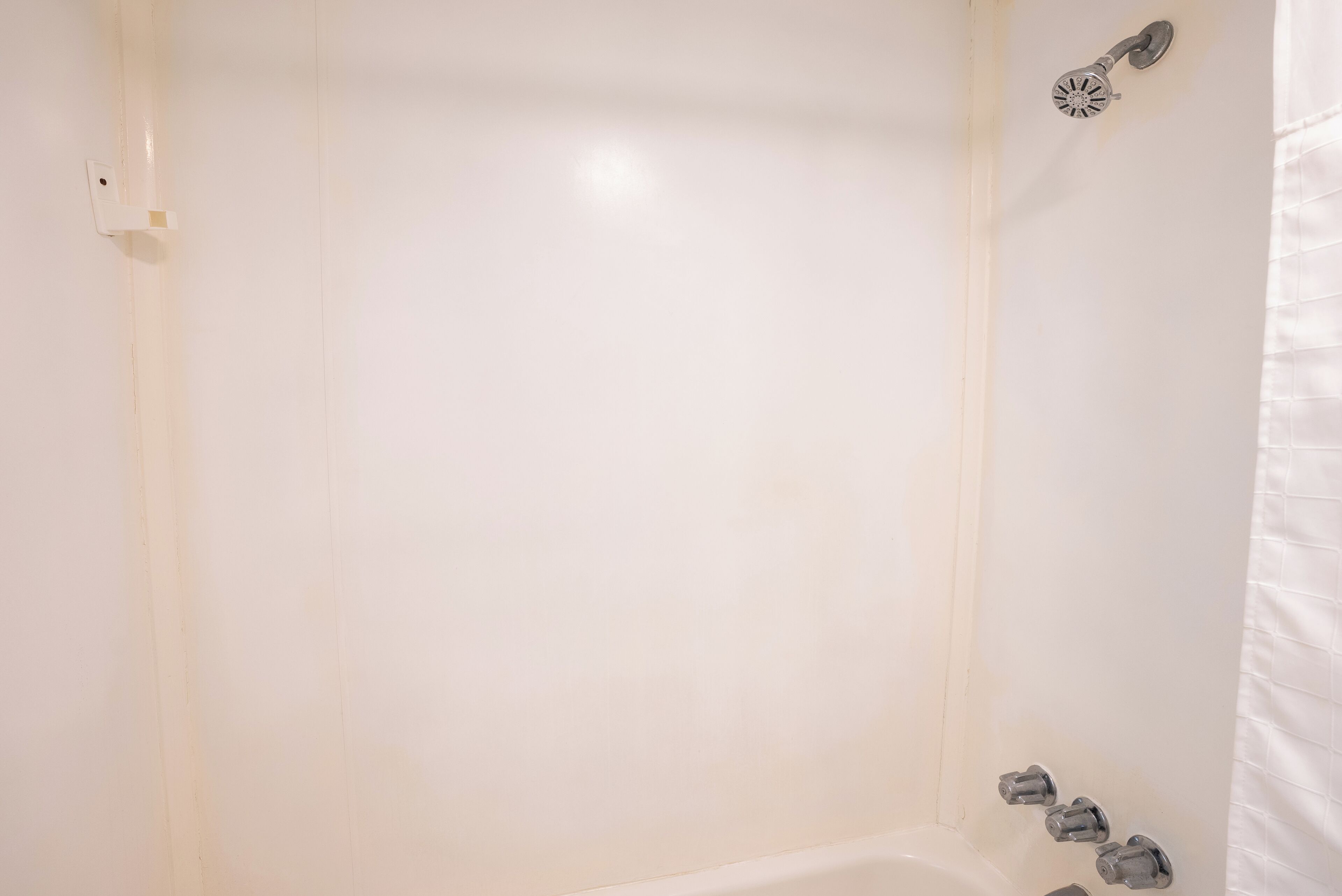 Un baño con una bañera blanca, cabezal de ducha y un perchero.