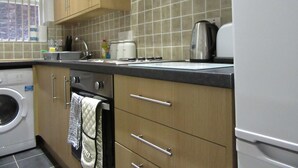 Eine Küche mit Holzausstattung, einer Waschmaschine, einem Wasserkocher und einem Toaster.