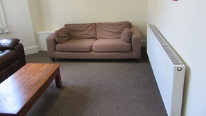 A living room with a brown sofa, a wooden coffee table, and two wall-mounted paintings.