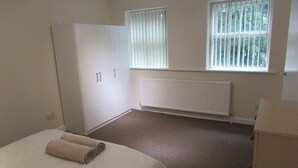 A bedroom with a bed, a wardrobe, a radiator, and a window with blinds.