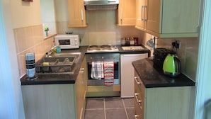A compact kitchen with a microwave, stove, sink, and a kettle. - No 7 (Liverpool)