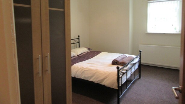 Ein Schlafzimmer mit Bett, Fenster und Tür.