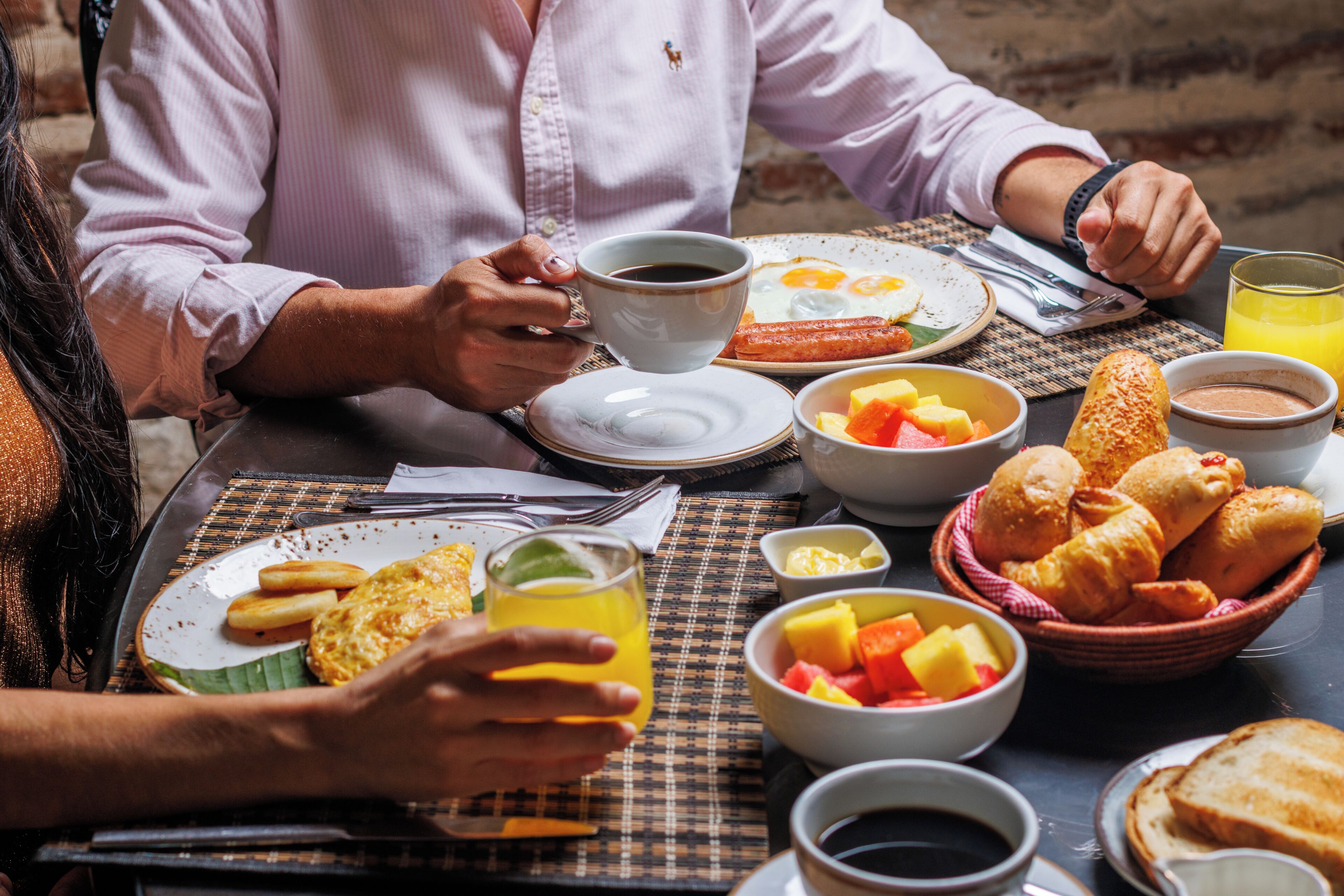 Una mesa de comedor con platos de comida, una taza de café y un vaso de jugo de naranja.