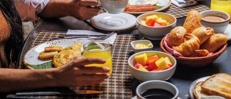 Una mesa de comedor con platos de comida, una taza de café y un vaso de jugo de naranja.