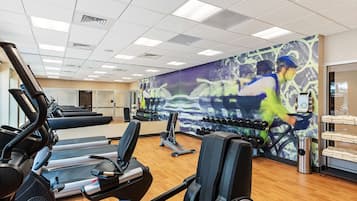 Une salle de sport équipée de tapis de course, d’haltères et d’appareils d’exercice.