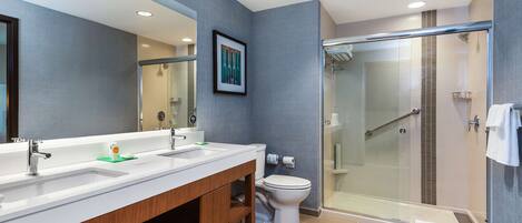 A modern bathroom with a double sink vanity, a toilet, and a glass-enclosed shower area.