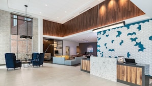 Een moderne lobby met een receptiebalie, een zithoek en een groot raam.
