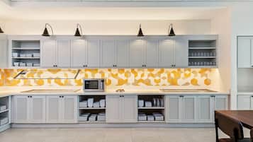 A modern kitchen with white cabinets, a microwave, and a geometric backsplash.