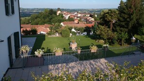 A residential area with a view of a village, a white building with green shutters, and a well-maintained lawn with potted plants. - Moonfrà (Antignano)