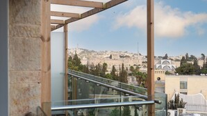 A view from a balcony with a metal railing, overlooking a cityscape with historical buildings and a mosque. - King David Court - Isrentals (Jerusalem)