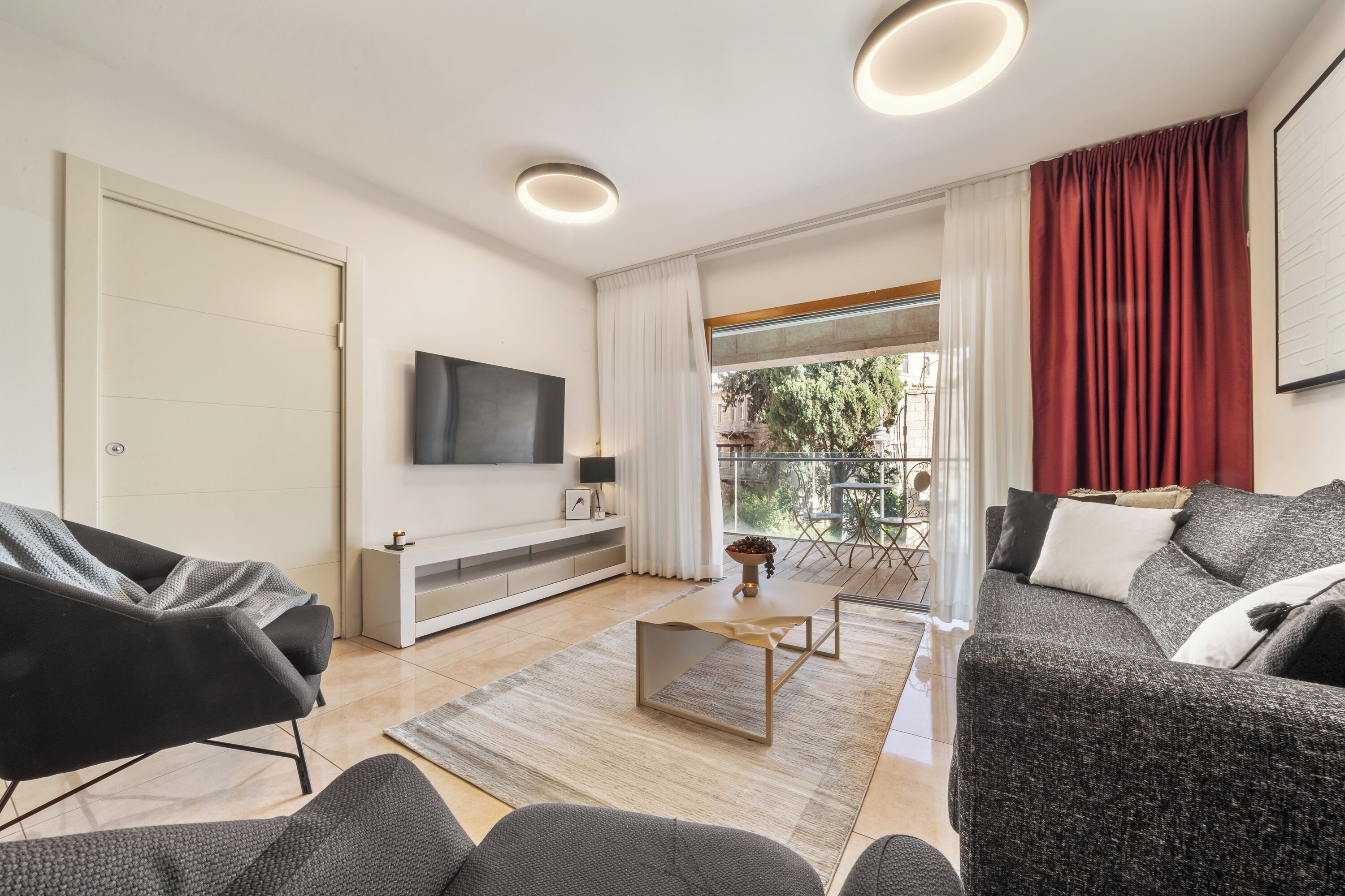 Una sala de estar moderna con un sofá, una mesa de centro y un televisor montado en la pared.