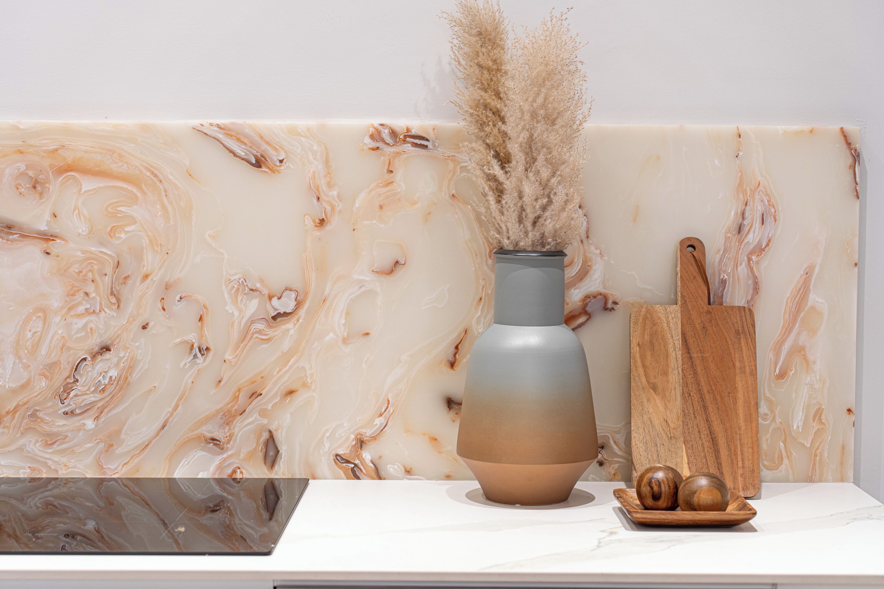 A marble wall with a vase and wooden objects on a white surface.