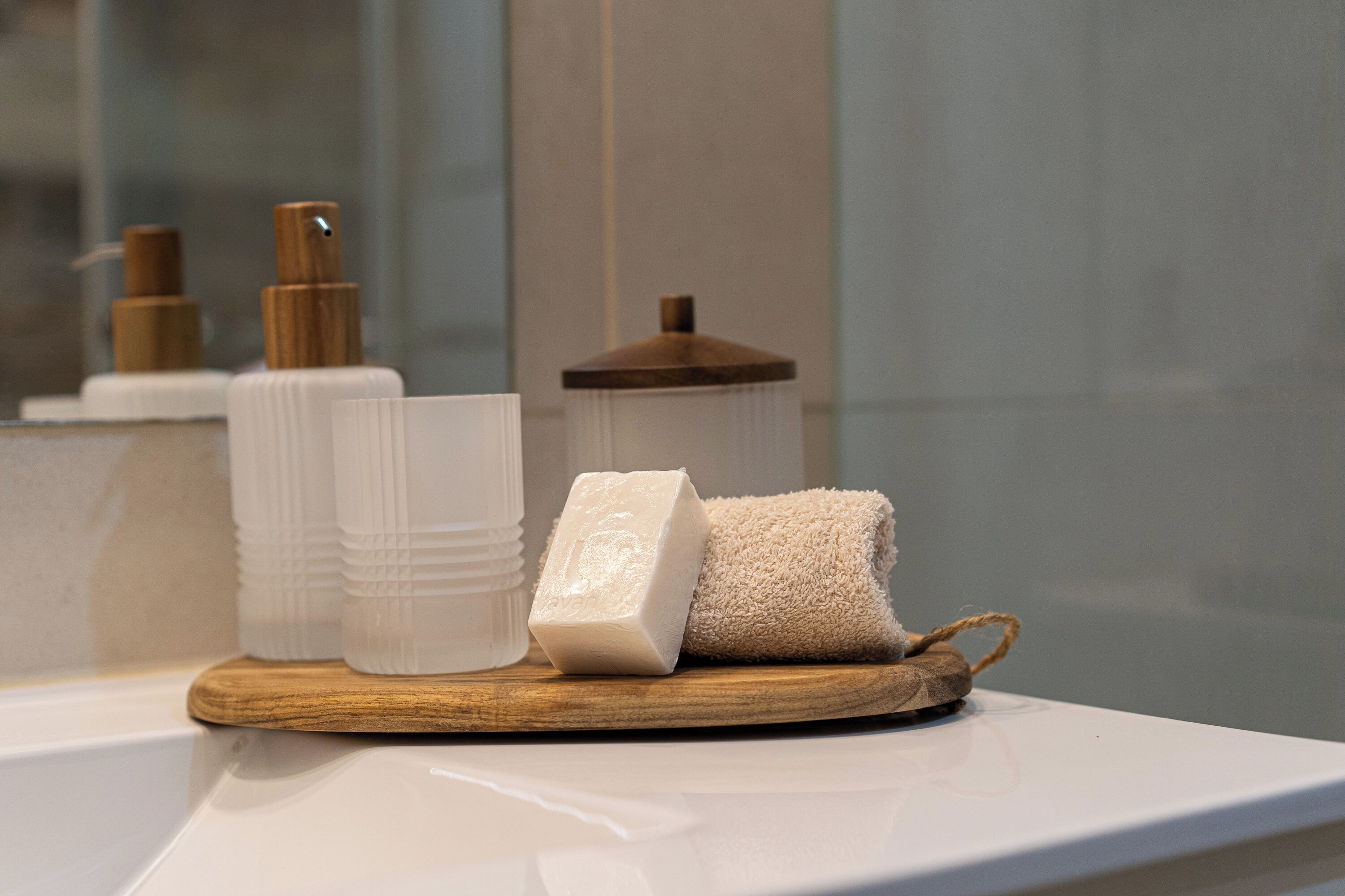 Un plateau en bois avec un savon et une serviette, posés sur le comptoir d’une salle de bain.