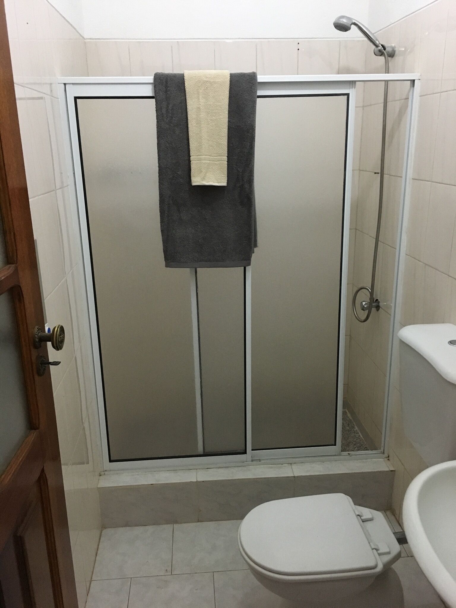 A bathroom with a shower enclosure, toilet, and sink.