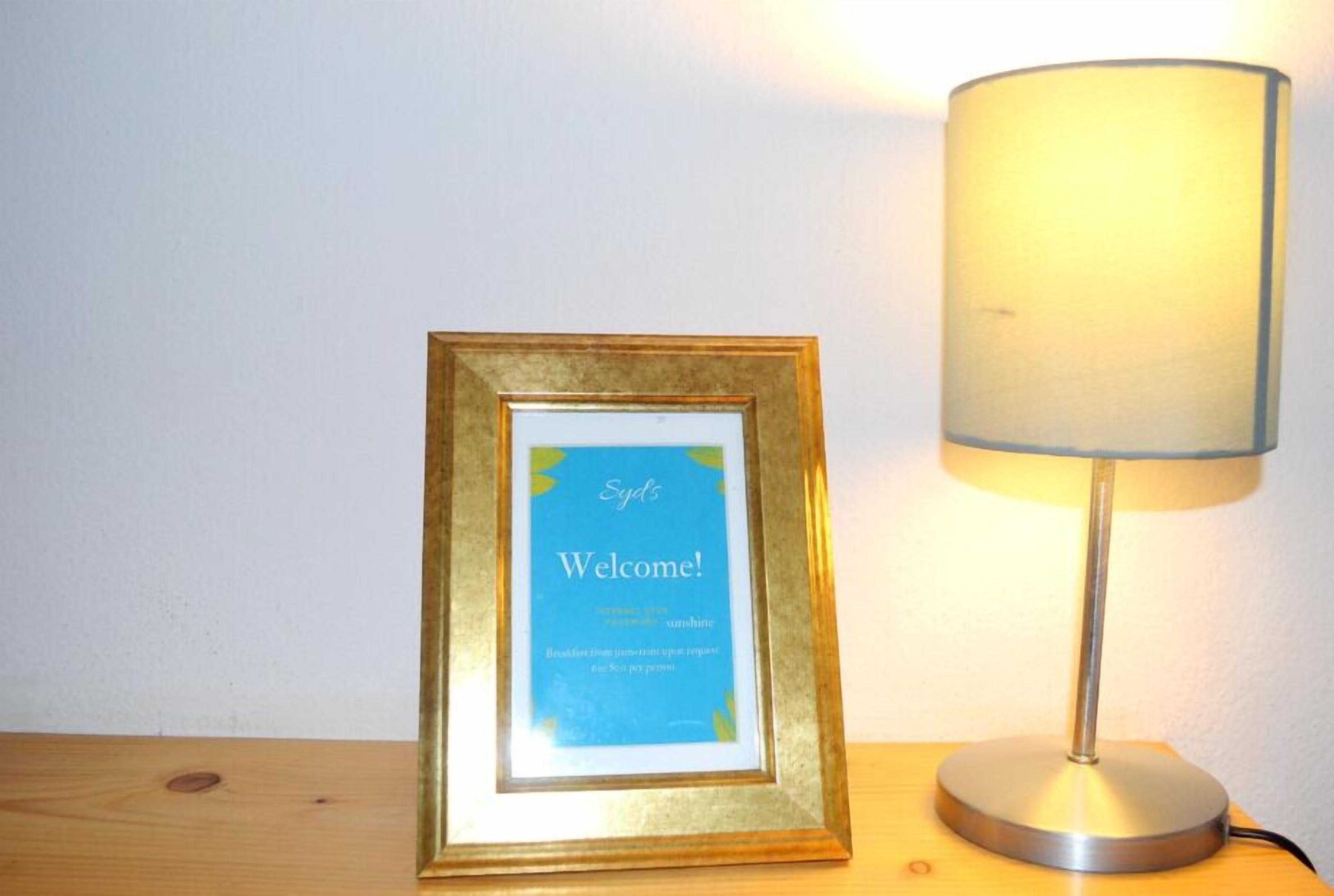 Een lijst met een welkomstbord en een lamp ernaast.
